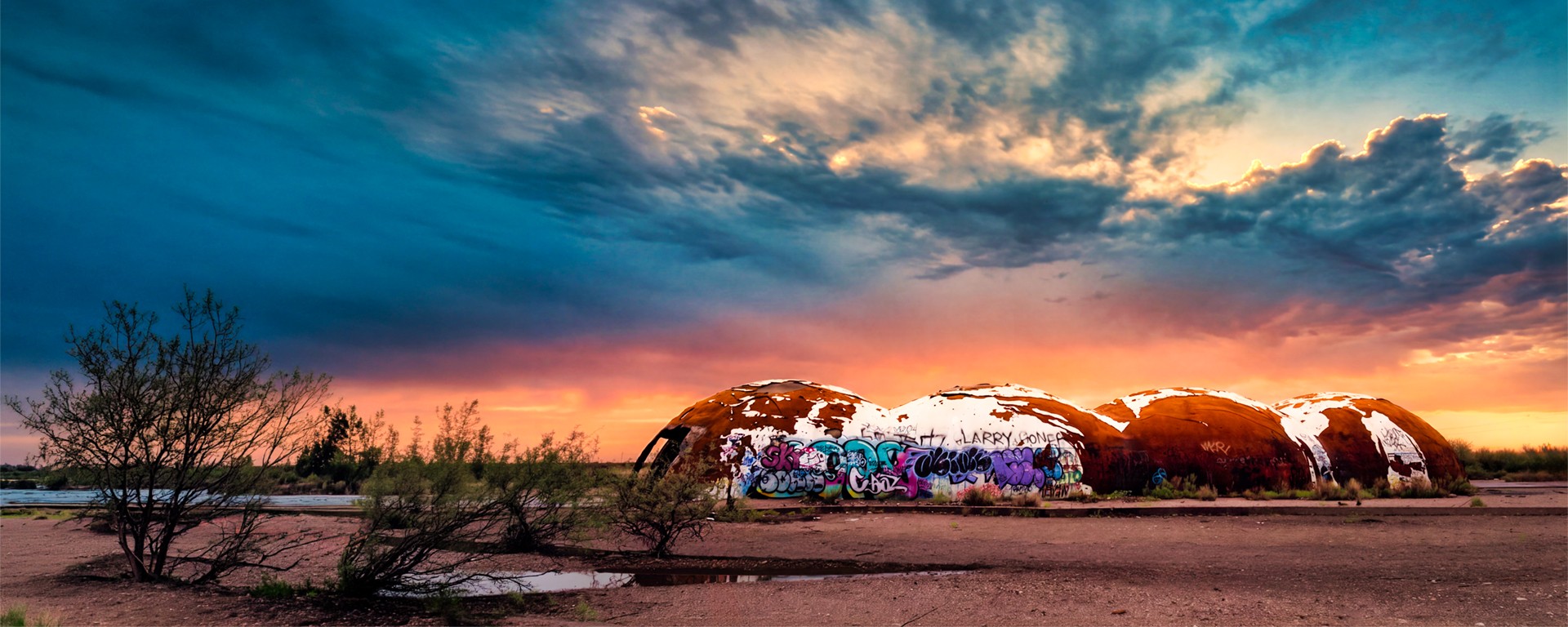 Abandoned domes beneath a vivid blue and orange sunset